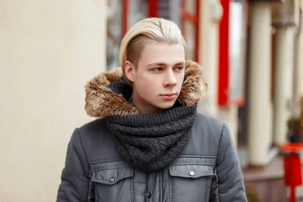 Handsome young guy with hair in a fashionable winter jacket with — Stock Photo, Image