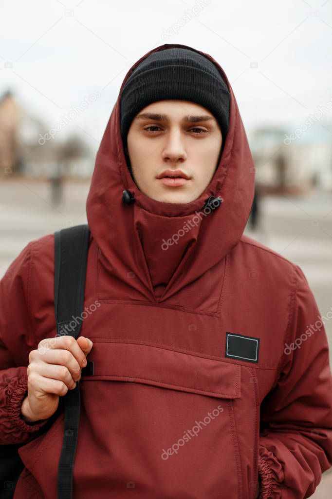 Street portrait of a fashionable guy in a stylish red jacket wit