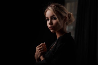 Karanlık bir odada siyah giysili bir saç kesimi ile güzel şık kız