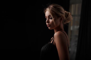 Karanlık bir odada siyah elbiseli seksi genç güzel kız