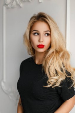 Moda güzel genç kadın kırmızı dudaklı beyaz bir duvar yakınındaki şık siyah gömlekli