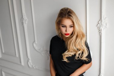 Genç ve güzel sarışın model kadın siyah moda gömlek beyaz duvarının yakınında bir saç modeli ile