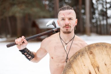 Bir balta ve ormanın içinde ahşap bir kalkan ile eski savaşçı