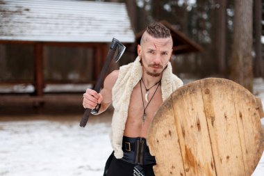 Eski savaşçı bir balta ve bir kalkan bir kış gününde ormanda bir yara izi olan bir adam