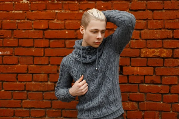 Elegante hombre guapo en un suéter de punto de moda cerca de un bri rojo — Foto de Stock