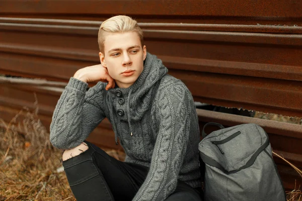 Stilig ung man i en trendig stickad tröja med en ryggsäck s — Stockfoto