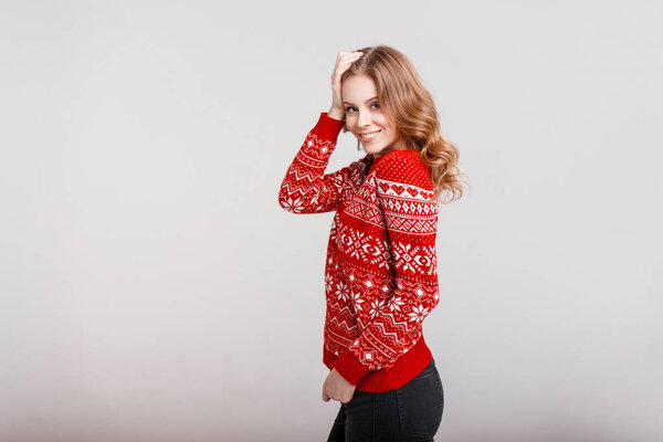 Beautiful young happy woman in a fashion vintage red sweater on a gray background in the studio