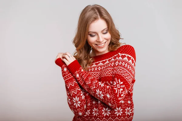 Молодая девушка в винтажном красном свитере с орнаментом на сером фоне в студии — стоковое фото