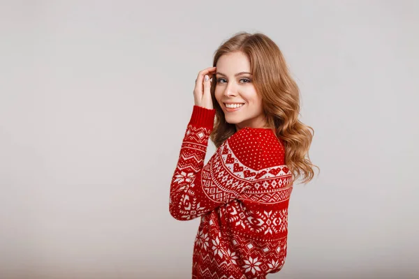 Happy young woman in a trendy fashion winter red sweater on a gray background — Stock Photo, Image