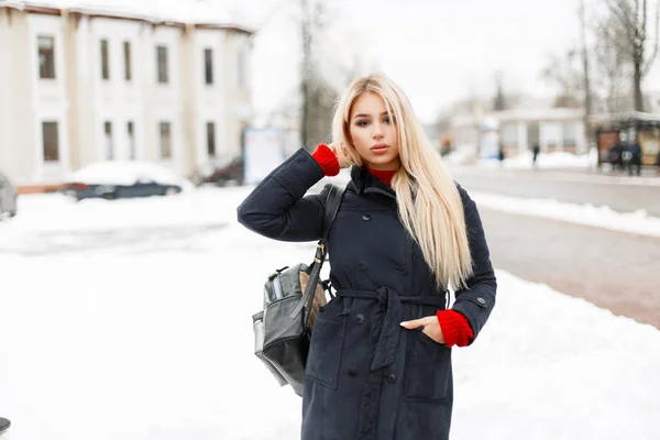 Menina da moda jovem bonita em um casaco elegante com um saco andando na cidade — Fotografia de Stock