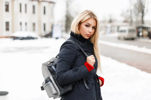 Bellezza giovane modella donna alla moda in un cappotto di moda con una borsa alla moda in posa in città — Foto Stock