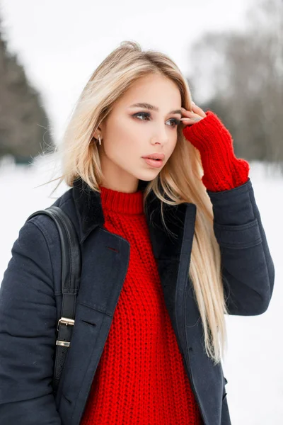 Menina modelo muito jovem em casaco de moda com uma camisola vermelha com um saco elegante caminha no parque — Fotografia de Stock