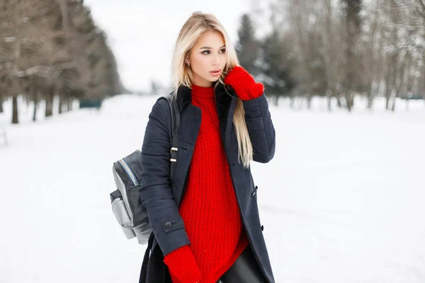 Şık bir çanta ile kırmızı bir kazak trendy moda paltolu oldukça stil sahibi genç kadın yürüyor — Stok fotoğraf