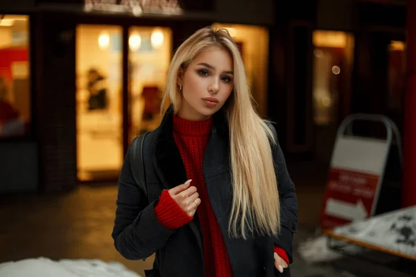 Młody model blond kobieta moda vintage płaszczyk czerwony sweter z worek spaceru po mieście w godzinach wieczornych — Zdjęcie stockowe