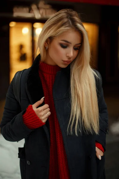 Jeune belle femme en manteau tendance posant en ville près de la vitrine le soir — Photo
