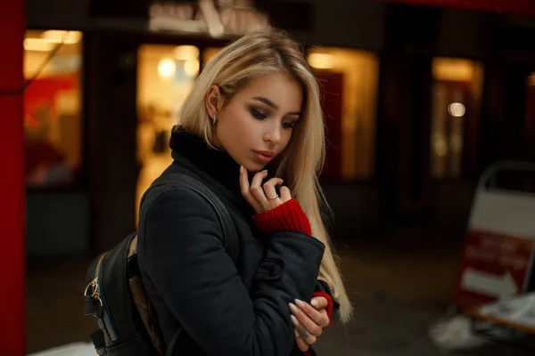 Belle jeune femme modèle américain en manteau de mode à la mode avec sac élégant posant en ville — Photo