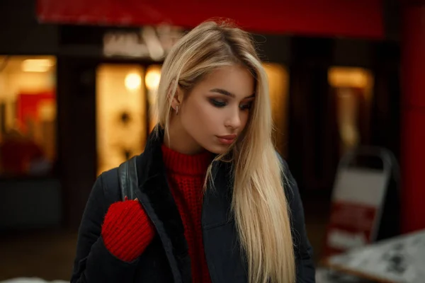 Moda güzel genç kadın siyah zarif paltolu mağaza yakınındaki akşam kırmızı bir kazak — Stok fotoğraf