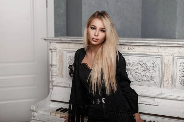 Joven hermosa mujer de moda en negro vestido elegante posando cerca de piano vintage —  Fotos de Stock