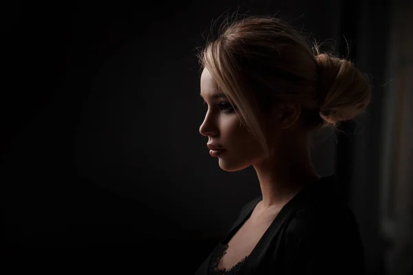 Retrato de uma bela jovem mulher em um vestido preto moda em um fundo preto. Perfil feminino — Fotografia de Stock