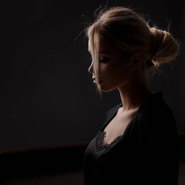 Young beautiful model woman with a hairstyle in a black fashion dress on a black background — Stock Photo, Image