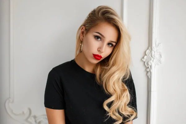 Retrato de moda de una joven hermosa mujer con una camiseta negra cerca de una pared blanca —  Fotos de Stock