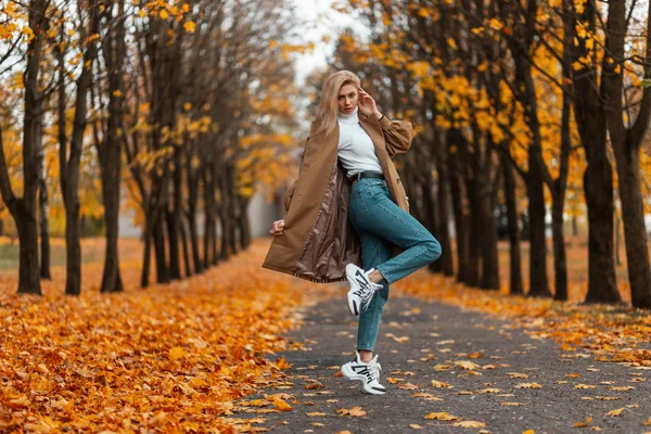 Modelo de jovem mulher elegante em roupas elegantes em sapatos da moda no parque em um dia quente de outono. Menina loira urbana na moda gosta de um passeio na floresta. Outono juventude moda feminina. Estilo casual . — Fotografia de Stock