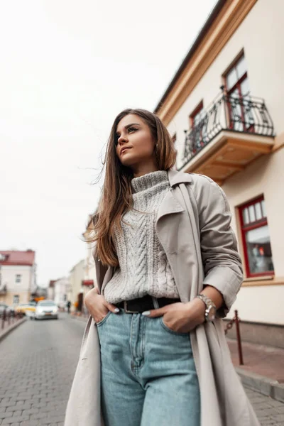 European young modern woman in stylish autumn-spring clothes stands on a street in the city near vintage buildings. Trendy girl model in fashionable outerwear outdoors. Seasonal women's clothing. — 스톡 사진