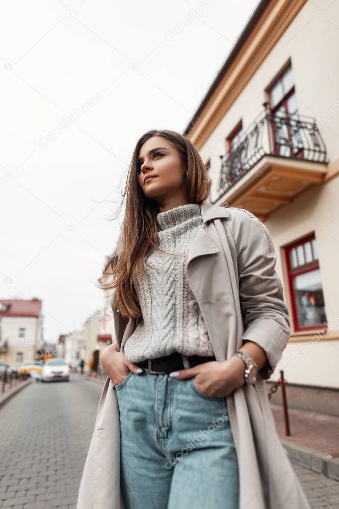Fotos de Mujer europea joven y moderna en ropa elegante otoño-primavera se  encuentra en una calle de la ciudad cerca de edificios antiguos. Modelo de  chica de moda en ropa exterior de