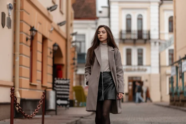 Mooie jonge vrouw in modieuze buitenkleding loopt op straat. Schattig meisje model in stijlvolle kleding is reizen op de stad in de buurt van vintage gebouwen. Trendy nieuwe collectie lente-herfst kleding. — Stockfoto