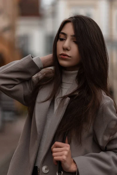 도시 밖에 가방 이 있는 유행하는 코트를 입은 예쁜 젊은 여성의 초상화. 아름다운 여성 모델 이 가을에 야외에서 포즈를 취하는 모습. — 스톡 사진