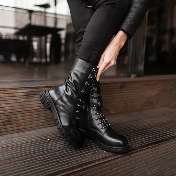 Femme à la mode se tient dans un magasin et mesure chaussures d'automne. Gros plan de jambes féminines en jean élégant en cuir tendance noir lacets bottes. Nouvelle collection saisonnière de chaussures pour femmes. — Photo