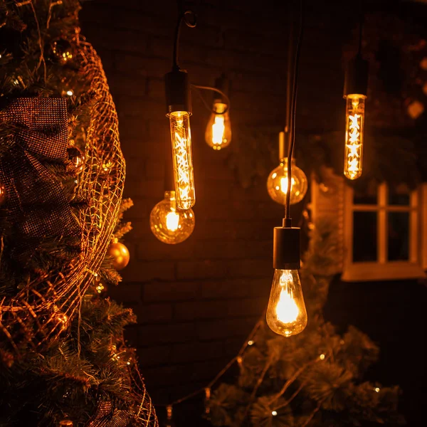 Hermosa habitación oscura con lámparas viejas con luz amarilla y un árbol de Navidad con juguetes dorados y guirnaldas vintage. Preparándose para las vacaciones de invierno. Feliz año nuevo . — Foto de Stock