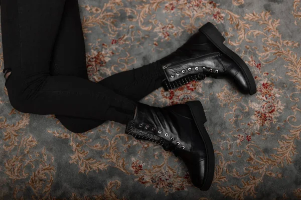 Vue de dessus sur les jambes fines d'une jeune femme en chaussures en cuir à la mode en jean noir élégant dans un studio. Tendance moderne jeunesse nouvelle collection de bottes saisonnières. Chaussures automne-hiver. Style décontracté . — Photo