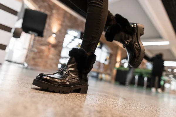 Молода сучасна жінка гуляє по торговому центру в шкіряних модних чорних теплих зимових черевиках з хутром в старовинних джинсах. Крупним планом жіночі ноги в стильному взутті. Нова сезонна колекція . — стокове фото