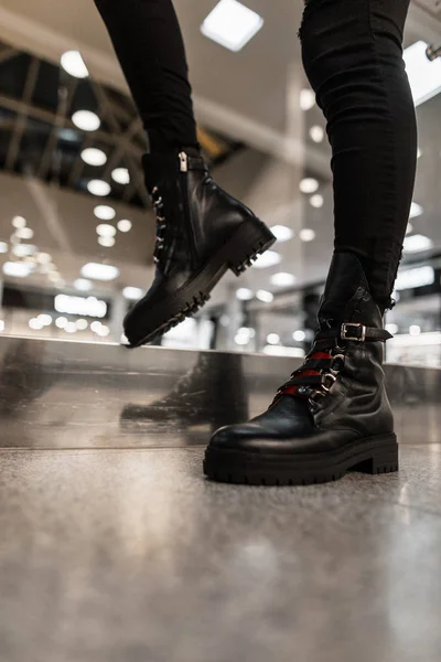 Fiatal nő egy divatos fekete bőrcsizmában, piros cipőfűzővel, vintage farmerben pózol egy boltban. Közelkép a női lábak divatos szezonális cipő. Őszi-téli cipő. Új gyűjtemény. — Stock Fotó