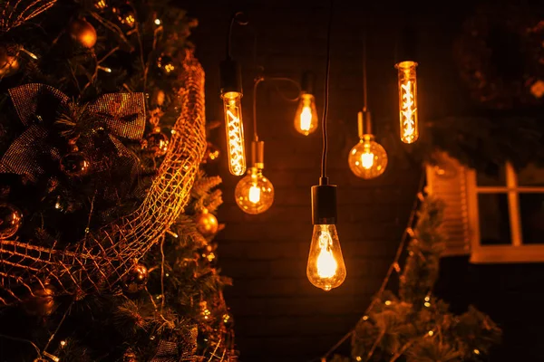 Acogedora habitación con un árbol de Navidad con guirnaldas doradas con lámparas vintage con bolas de espejo con luz amarilla por la noche. Feliz Navidad y Feliz Año Nuevo. Primer plano . — Foto de Stock