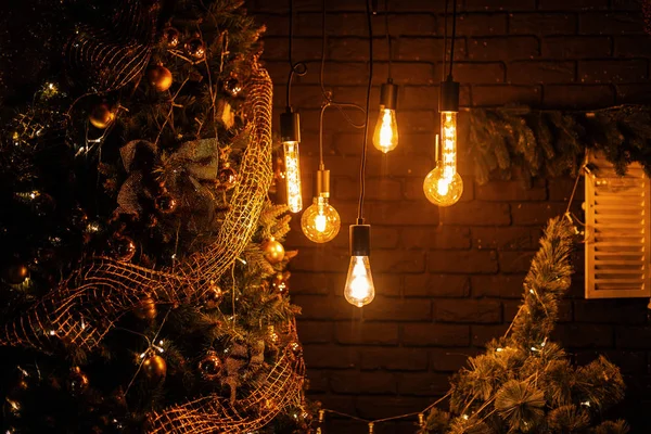 Acogedora sala de estar está decorada con numerosas luces vintage para la celebración del Año Nuevo. Interior estudio de Navidad. Árbol de Navidad está decorado con una guirnalda vintage de oro y hermosos juguetes . — Foto de Stock