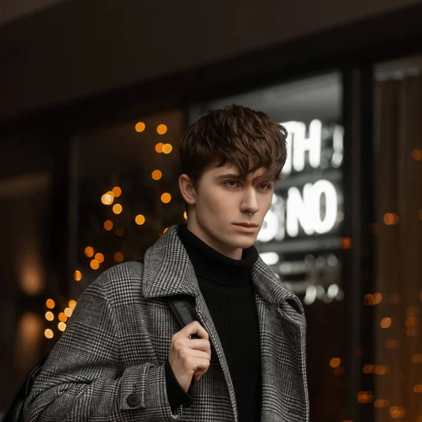 Retrato de la cara de un joven guapo en ropa interior de invierno elegante con un peinado elegante en el fondo de un escaparate con luces vintage. Un tipo atractivo en la ciudad. Fin de semana de Año Nuevo — Foto de Stock