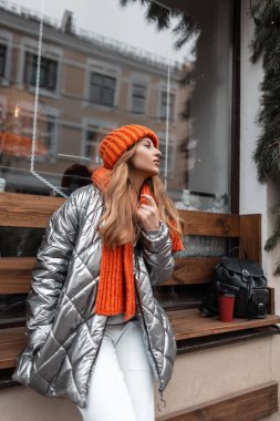 Şık kış kıyafetleri içinde güzel bir genç bayan Noel 'de vintage pencereli binanın yanında duruyor. Şehrin dışında poz veren modaya uygun mevsimlik gösterişli kıyafetleri olan şehir kızı..