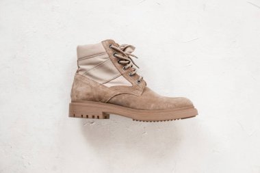 Beyaz arka planda şık bir bej süet dantelli bot. Yakın plan. Şık erkek ayakkabıları. Bahar modası.
