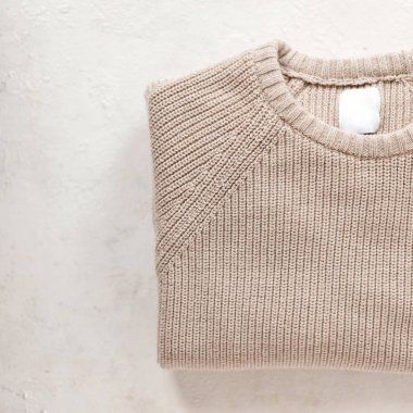 Havalı bej örülmüş kalın bir süveterin üst görüntüsü. Kış modasına uygun erkek örgü giysileri. Modaya uygun gençlik örgüsü. Ayrıntılar. Yakın plan..