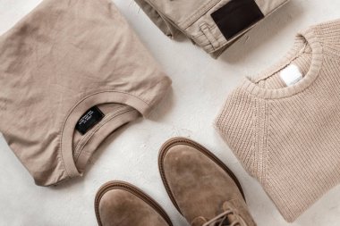 Klasik klasik pamuklu gömlek, örgü örülmüş yün süveter, moda botları ve masa üzerinde moda pantolonları. Yeni bahar erkek kıyafetleri ve modern ayakkabılar koleksiyonu. Üst Manzara. Yakın plan.
