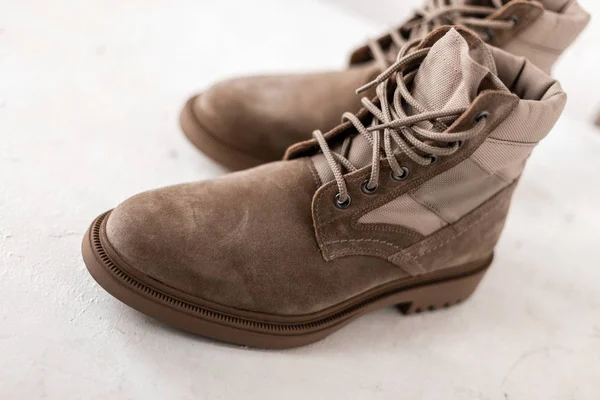Men's beige suede boots with shoelaces on a white background in studio. Close-up of men's seasonal luxury shoes. Details. New winter collection footwear. — Stock Photo, Image
