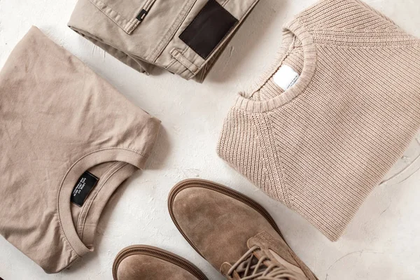 Group of fashionable clothes on the table. Beige denim pants, cotton shirt, woolen knitted vintage sweater and beige suede leather boots lie on the white floor. Classic elegant menswear. Top view. — 스톡 사진