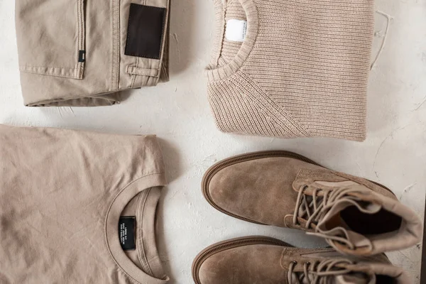 Bovenaanzicht op een gebreide trui met beige suède laarzen met trendy katoenen broek met een stijlvol shirt op een witte achtergrond. Elegante casual lentecollectie voor moderne trendy mannen. Stijlvolle look. Close-up — Stockfoto