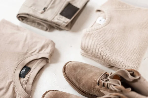 Suede men's stylish boots with fashionable beige casual sweaters with classic pants on a white floor. Trendy spring collection in pastel colors for men. Youth modern fashion. Retro style. Close-up. — ストック写真