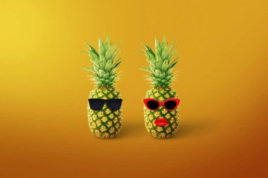 Stylish funny couple of pineapple hipster in sunglasses on a yellow background. Creative summer vacation. Healthy lifestyle concept. Fashion fruit look