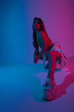 Güzel genç bayan dansçı şık ayakkabılar içinde neon mavisi pembe bir odada oturuyor. Moda dünyasındaki güzel modern kız modelleri çok renkli parlak disko ışıklarıyla iç mekanlarda giyerler..