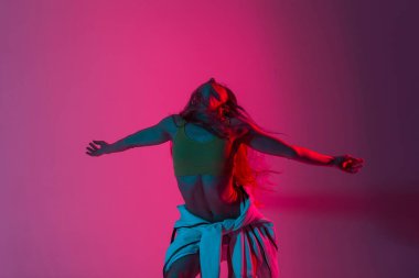 Moda mankeni genç ve güzel bir kadın spor giyim mankeni çok renkli ışıklarla dolu bir odada dans etmekten zevk alıyor. Parlak pembe neon ışıklarıyla dans eden şık, güzel, seksi kız..
