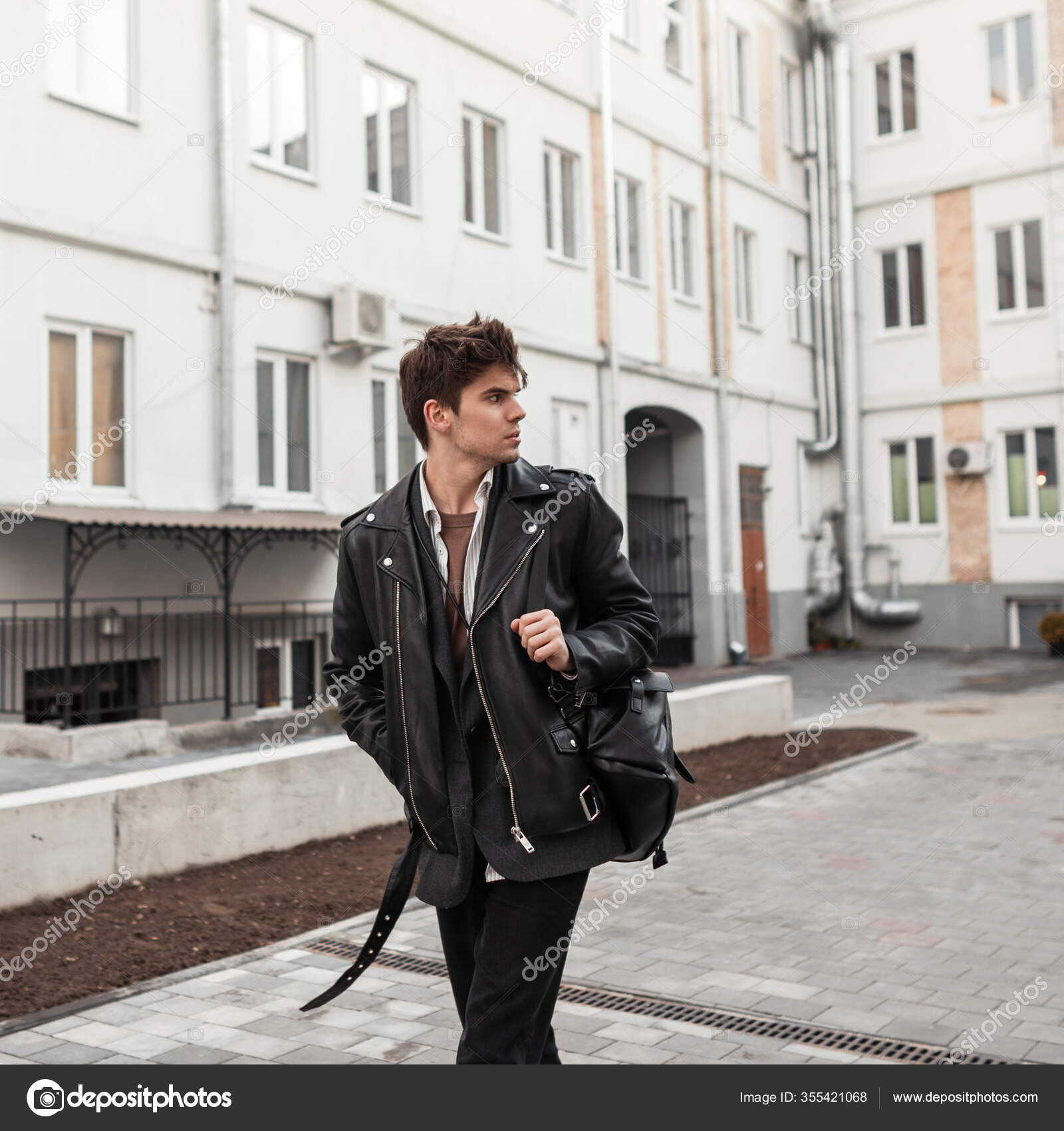 Hombre joven bastante urbano con estilo en ropa de jeans de moda en zapatillas  negras de moda con mochila de cuero
